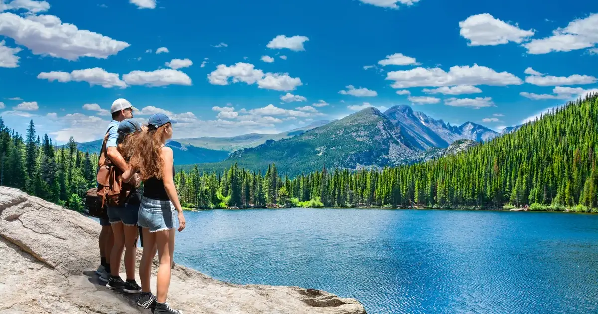 A family on a granite outcrop looking out over an alpine lake and mountain ridge